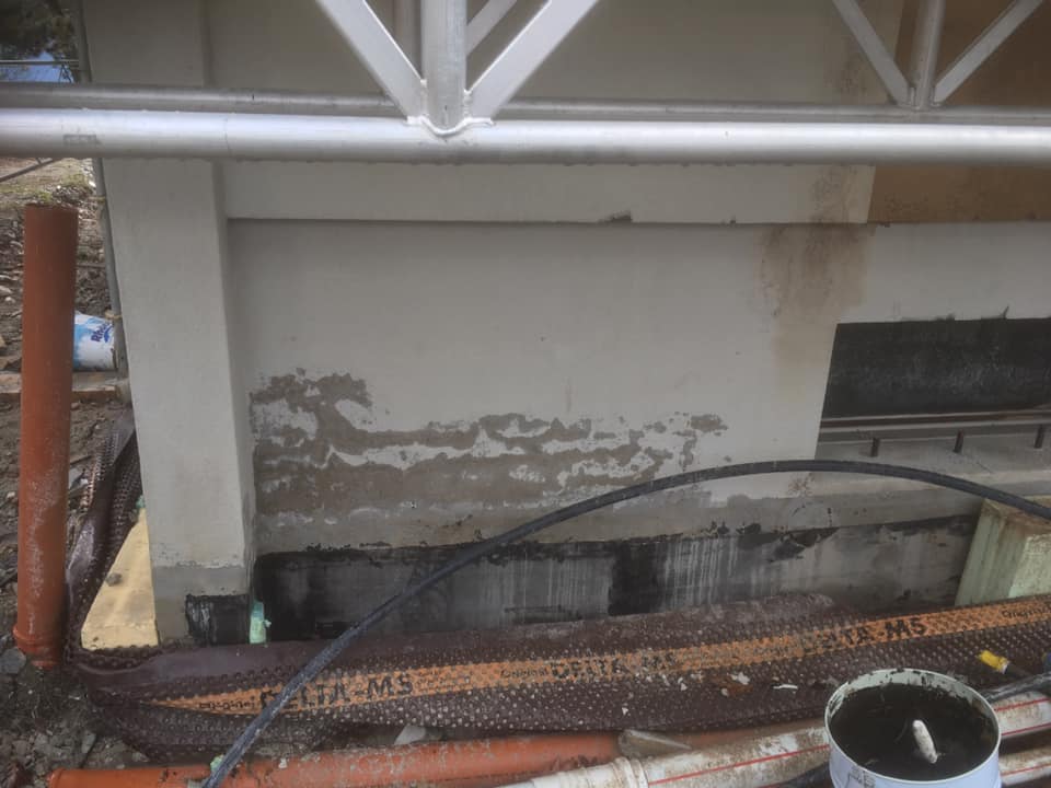 Mur avec traces d'humidité et tuyaux visibles.