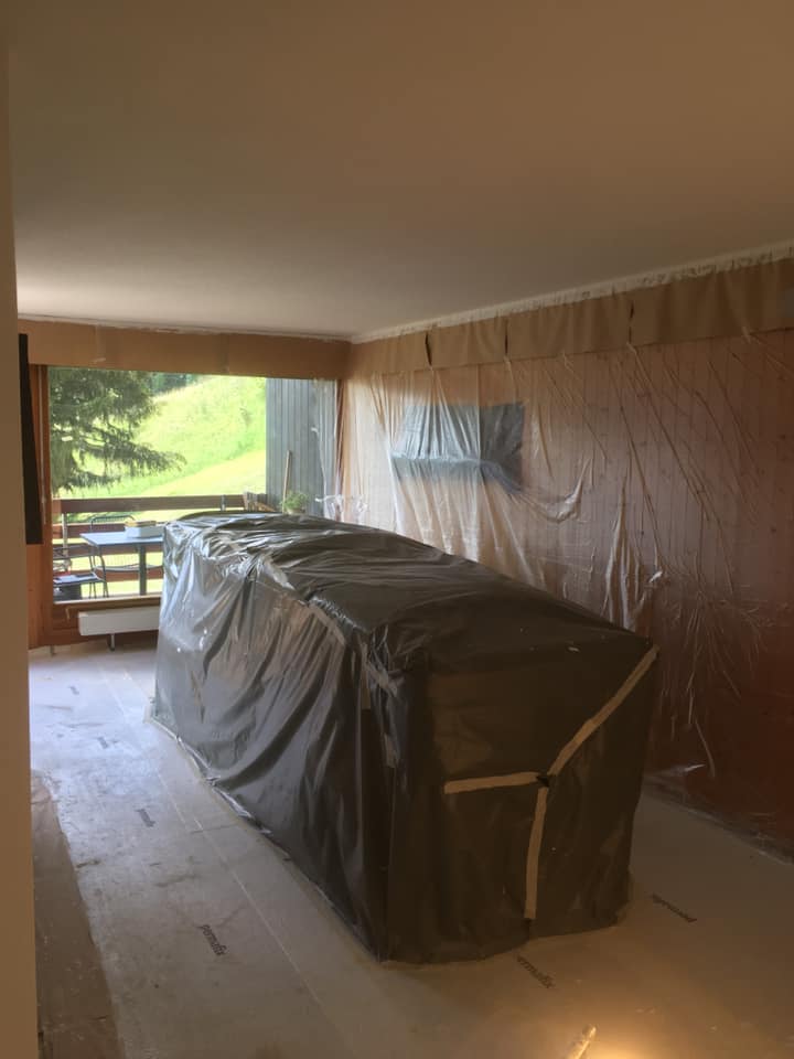 Salon en rénovation avec meubles bâchés.