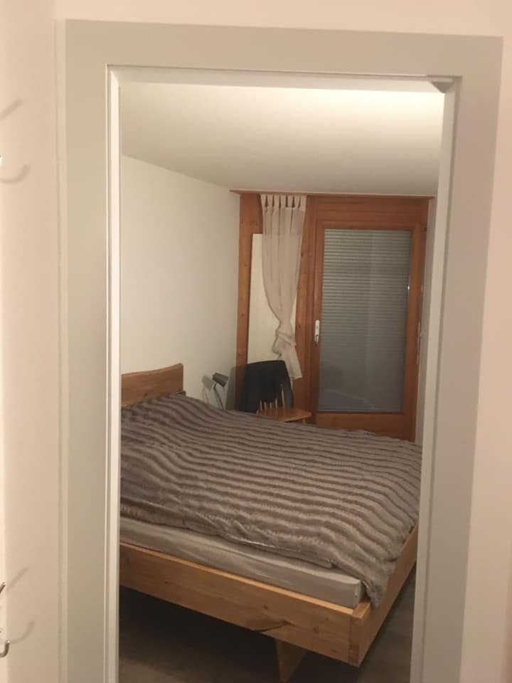 Chambre avec lit double, rideaux et fenêtre.