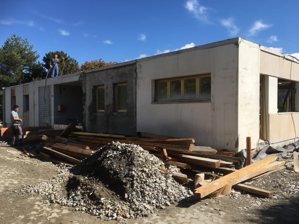 Bâtiment en construction avec ouvriers et matériaux.