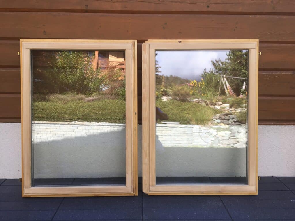 Deux fenêtres en bois reflétant le jardin