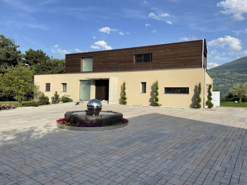 Maison moderne avec jardin et fontaine.