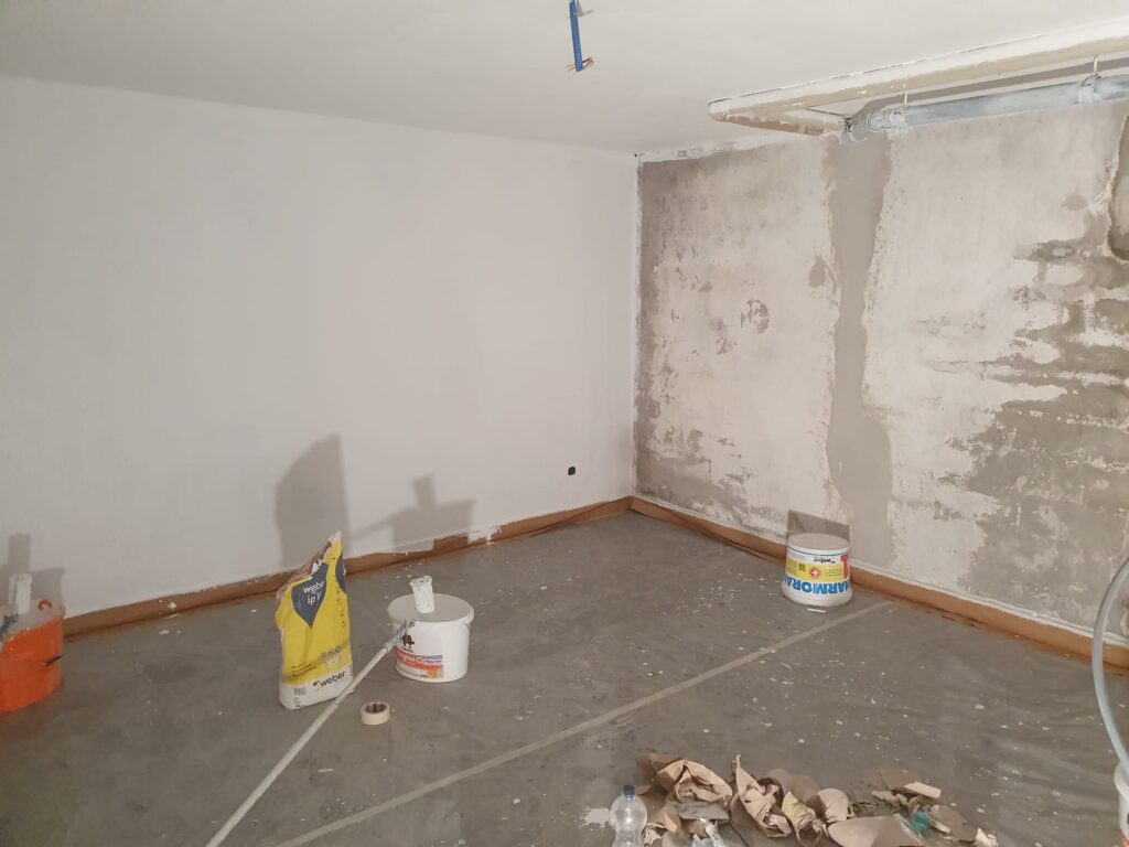 Mur partiellement rénové avec matériaux de construction.
